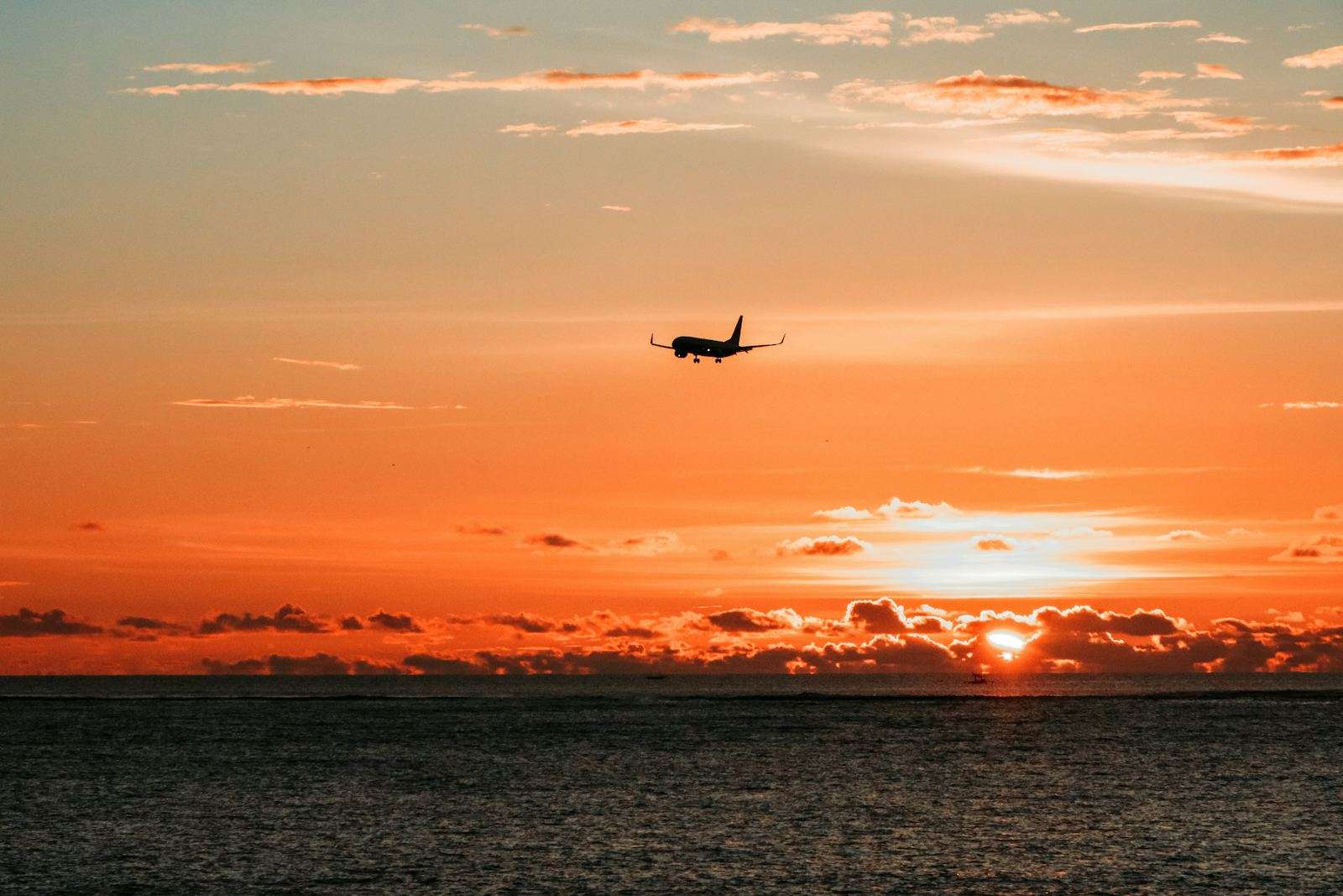 Airplane on approach at sunset over the ocean