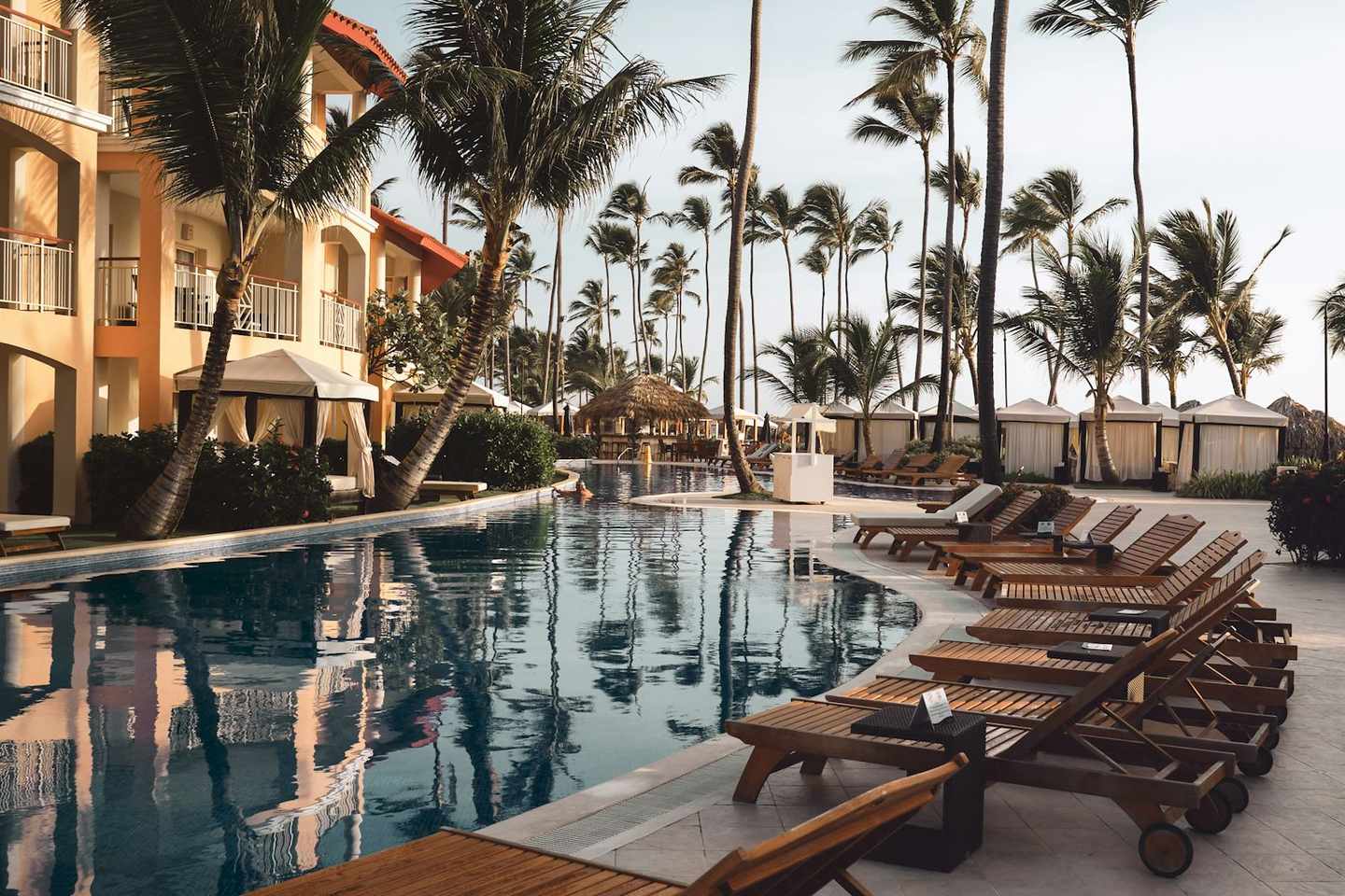 Palm-lined resort pool with loungers and cabanas