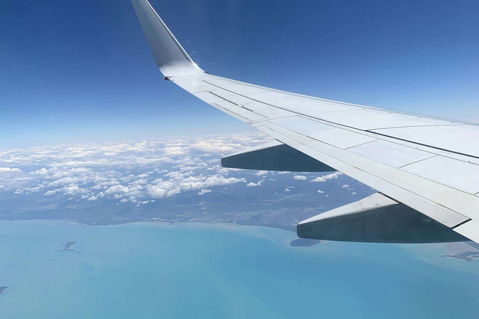 View over a turquoise coastline from an airplane wing